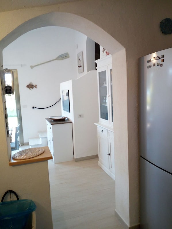 Una cocina con armarios blancos, un refrigerador y una encimera de madera.