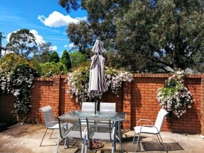 Enjoy al fresco dining on the patio, surrounded by lush greenery and a brick wall.