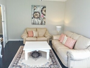 Relax in this inviting living room with two sofas, a coffee table, and a rug, featuring a beautiful painting above.