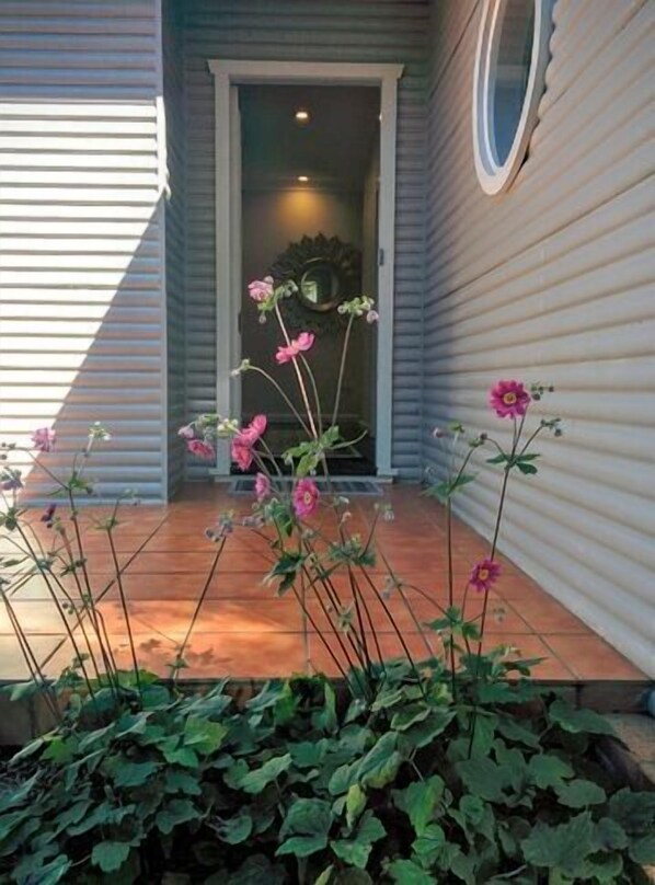Enter a charming home through the welcoming porch, surrounded by lush flowering plants.