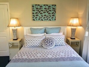 Cozy retreat with a neatly made bed, bedside lamps, and a nature-inspired wall art.