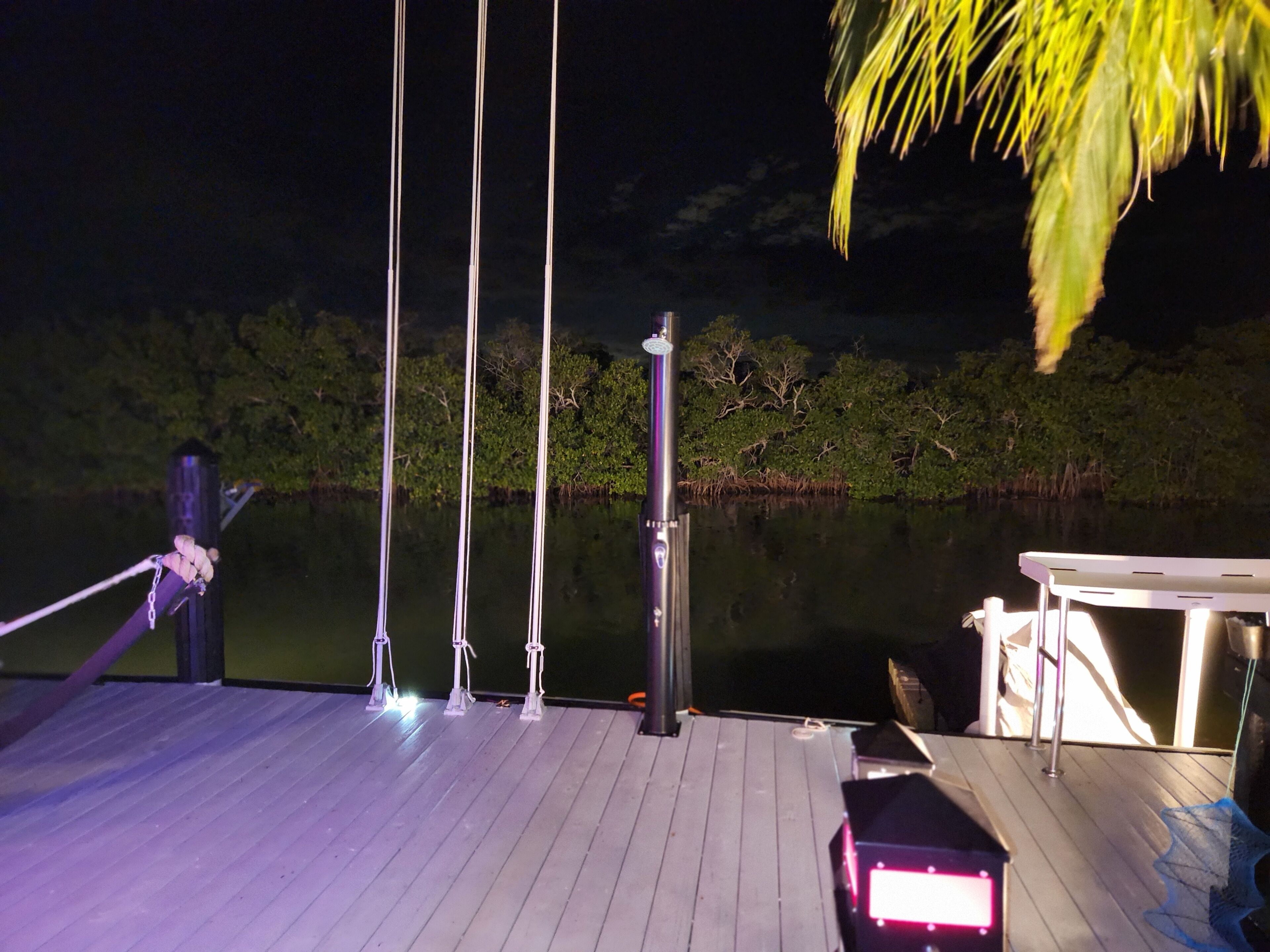 Een houten terras met een boot afgemeerd aan de rand, omgeven door kalm water en bomen.