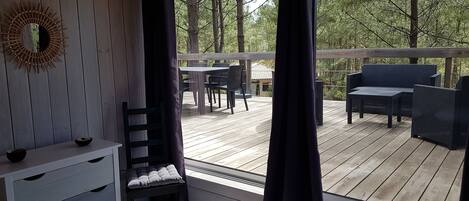Een slaapkamer met een bed, een kast en een raam met uitzicht op een terras met buitenmeubilair.