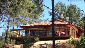 A two-story wooden cabin with large windows, a red roof, and a wooden deck. - Vacation home under the pines (moliets et maa)