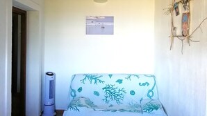 A room with a white sofa, a heater, and a wall-mounted picture. - Beachfront villa private pool   (Tertenia Marina di Tertenia)