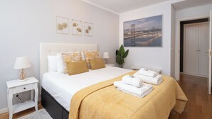 Quarto bem organizado com cama, mesas de cabeceira, um vaso de planta e um quadro na parede.