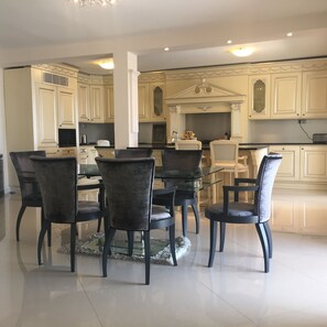 A dining area with a glass table surrounded by six chairs, a fireplace, and cream-colored cabinetry.