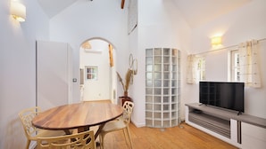 Un espacio habitable compacto con una mesa de comedor de madera, sillas, un televisor empotrado y un panel de vidrio esmerilado.