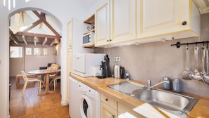 Cocina compacta con lavadora, lavaplatos y armarios de madera.