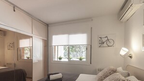 Quarto com uma cama, janela, obra de arte de bicicleta e aparelho de ar condicionado.