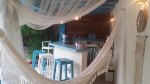 Une cuisine avec un plan de travail bleu, des tabourets de bar blancs et une décoration en macramé suspendue.