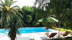 Une piscine avec deux chaises longues et un parasol vert.