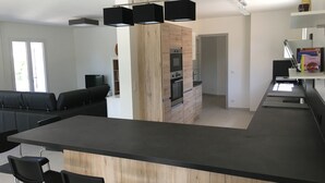 Una cocina moderna con una isla central, taburetes negros y un horno empotrado.