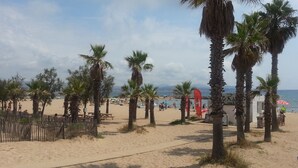 Una playa con palmeras, una cerca de madera y una caseta de salvavidas.