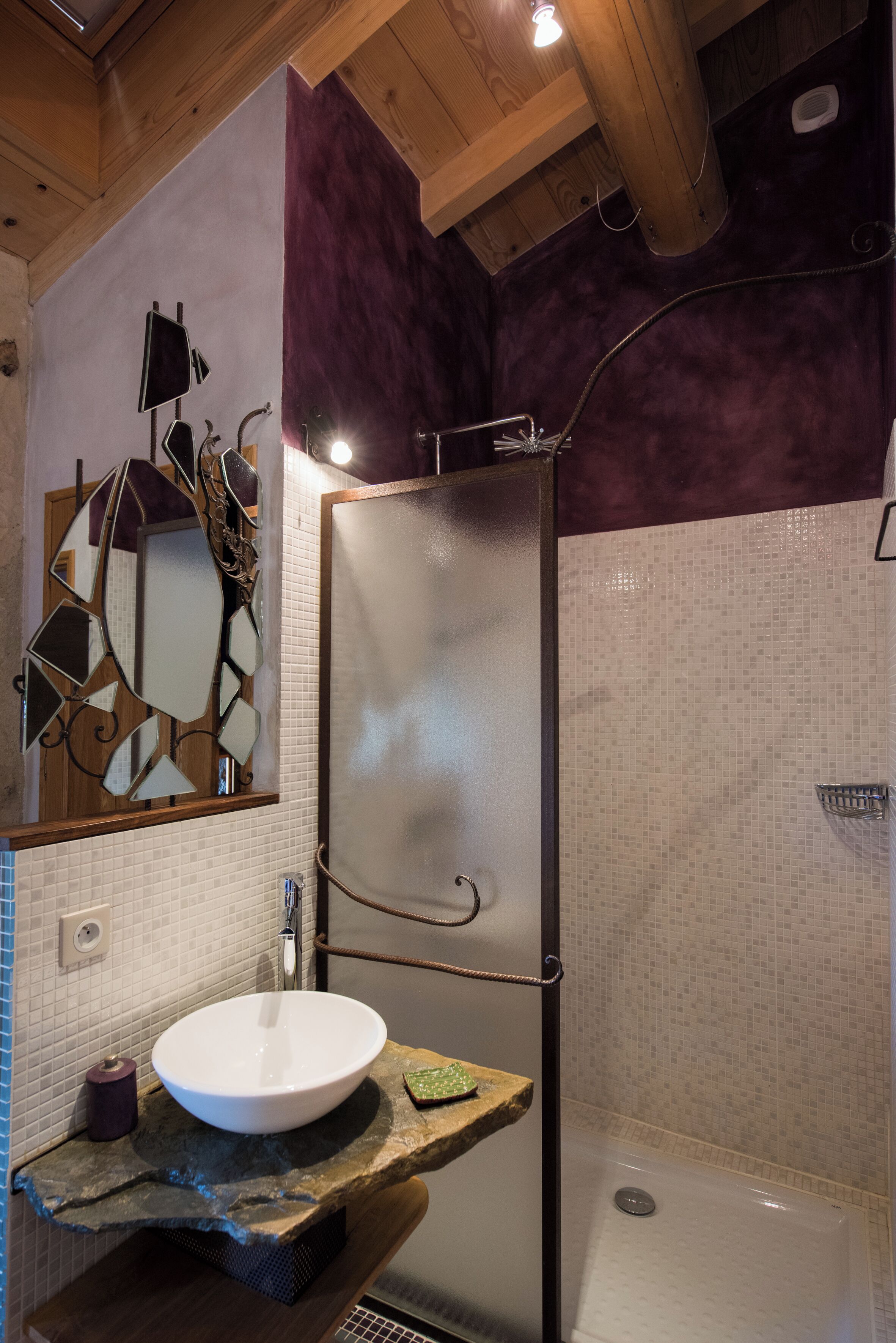 A bathroom with a white sink, a shower, and a mirror with a geometric design.