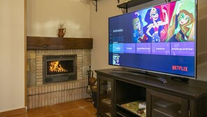 Un salon doté d’une cheminée, d’un téléviseur à écran plat affichant l’interface Netflix et d’une étagère au-dessus du téléviseur.