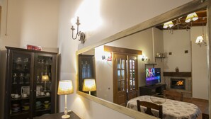A dining area with a table, chairs, a mirror, a cabinet with glassware, and a television.