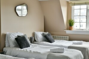 A hotel room with two beds, a mirror, a window with a plant, and a radiator. - Modern townhouse in Central Brighton, sleeping 15-32 guests. 2 Mins to beach (Brighton)