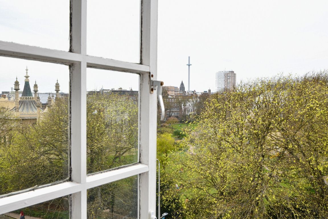 A view through a window with a cityscape, including a tower and buildings.