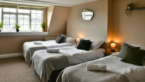 Ein Zimmer mit zwei Betten, einem Fenster mit Jalousien, einem Spiegel und einer Nachttischlampe.