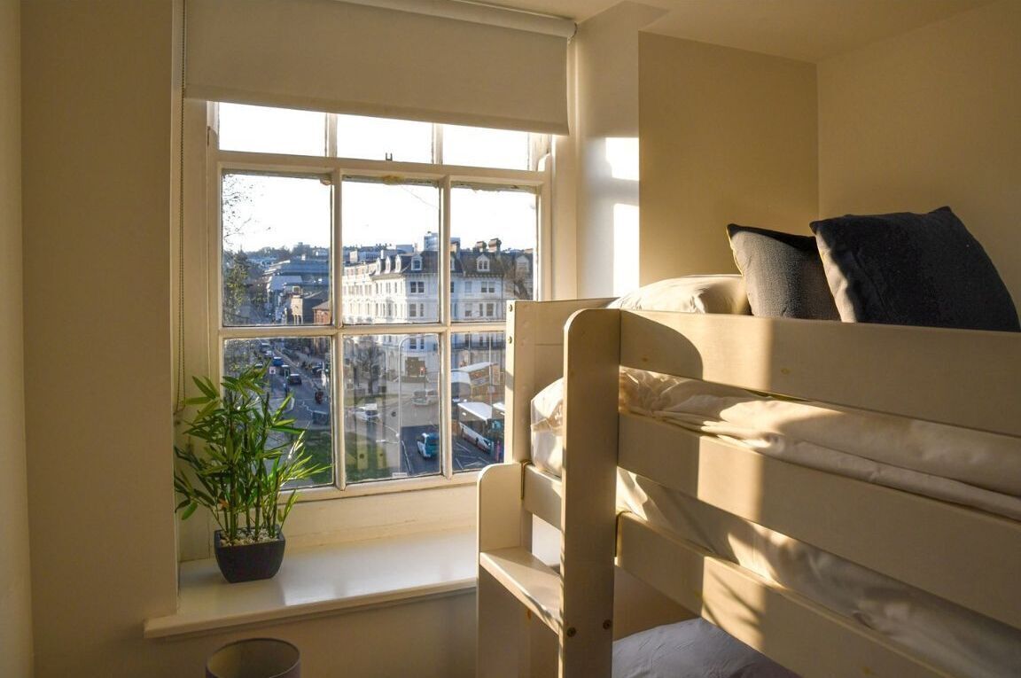 Ein Stockbett mit Blick auf eine Stadtlandschaft durch ein Fenster.
