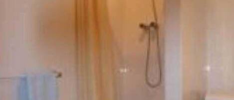 A bathroom with a shower, toilet, and washing machine.