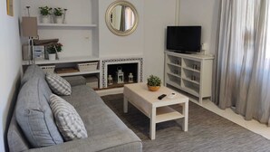 Een woonkamer met een bank, een televisie, een open haard en een spiegel.