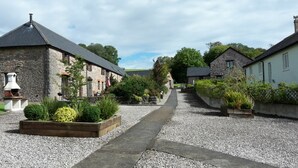 A stone building with a gravel pathway leading to a wooden door. - Gold Award winning cottage- with indoor heated pool and games area- pet friendly (Totnes)