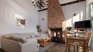 A living room with a sofa, coffee table, fireplace, TV, and dining area. - Gold Award winning cottage- with indoor heated pool and games area- pet friendly (Totnes)