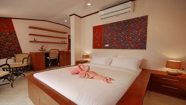 A hotel room with a large bed, a desk with a chair, a small table with a lamp, and a wall-mounted air conditioner. - Beachfront Resort: Villa 4-bdr, very spacious, only 20m to the beach. (Maenam)