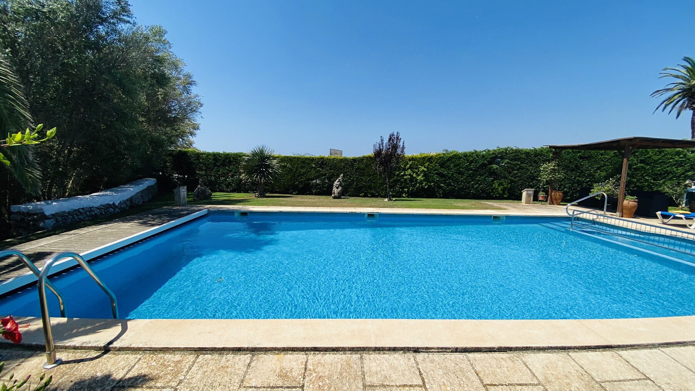 A rectangular swimming pool with a clear blue water surface, surrounded by a stone deck.