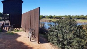 Una estructura de madera rústica con una pequeña torre, una valla de madera y una bicicleta estacionada cerca.