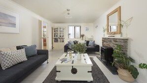 Ein Wohnzimmer mit einem dunklen Sofa, einem weißen Couchtisch, einem Kamin und einem Bücherregal.