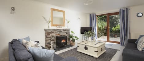 A living room with a stone fireplace, grey sofas, a coffee table, and a television.