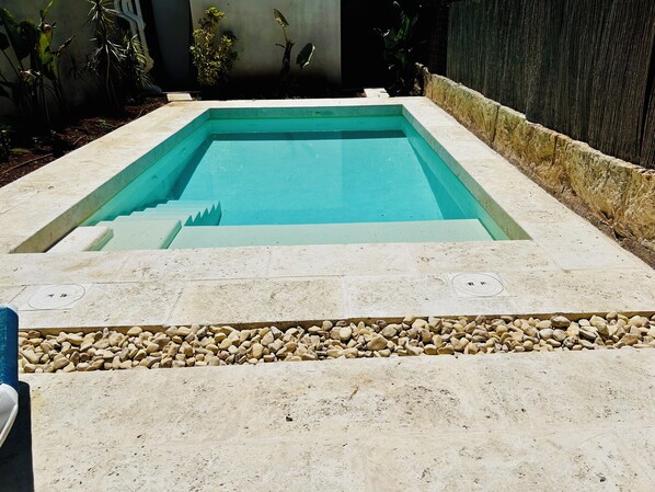 Una piscina rettangolare con bordo in pietra e scalini d'accesso.