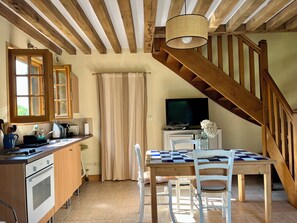 A kitchen with a wooden ceiling, a dining area with a checkered table, and a TV on a stand. - House with garden (Grangues)