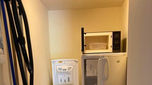 Una cocina compacta equipada con lavadora, microondas y refrigerador.