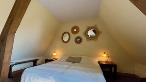 Un dormitorio con una cama, dos mesitas de noche y tres espejos colgados en la pared.