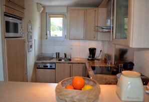 A kitchen with a microwave, coffee maker, and a bowl of fruit on the counter.