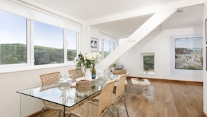 A dining area with a glass table, wicker chairs, and a view of the countryside. - A beautiful, double-fronted terrace house situated in Port Isaac. (Port Isaac)