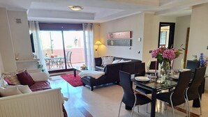 En rummelig opholdsstue med spisebord til fire, en sofa og et sofabord.