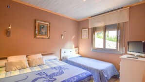 A bedroom with two beds, a television, and a window with blinds. - Club Villamar - Nice lower apartment in shared villa with private fenced swimming pool, small gym... (Macanet de la selva)