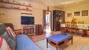 A living room with a television, sofa, and a dining area with a table and chairs. - Club Villamar - Nice lower apartment in shared villa with private fenced swimming pool, small gym... (Macanet de la selva)