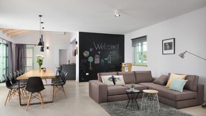 A modern living room with a large sofa, a dining table, and a blackboard with drawings. - Villa Roko  in Vodnjan (Vodnjan)