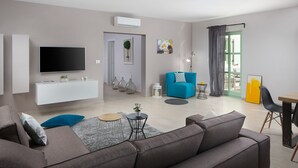 A modern living room with a flat-screen TV, a sofa, a blue armchair, and a dining area with a table and chairs. - Villa Roko  in Vodnjan (Vodnjan)