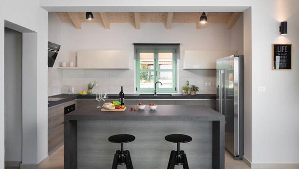 A modern kitchen with a central island, two bar stools, a refrigerator, and a window with green shutters. - Villa Roko  in Vodnjan (Vodnjan)