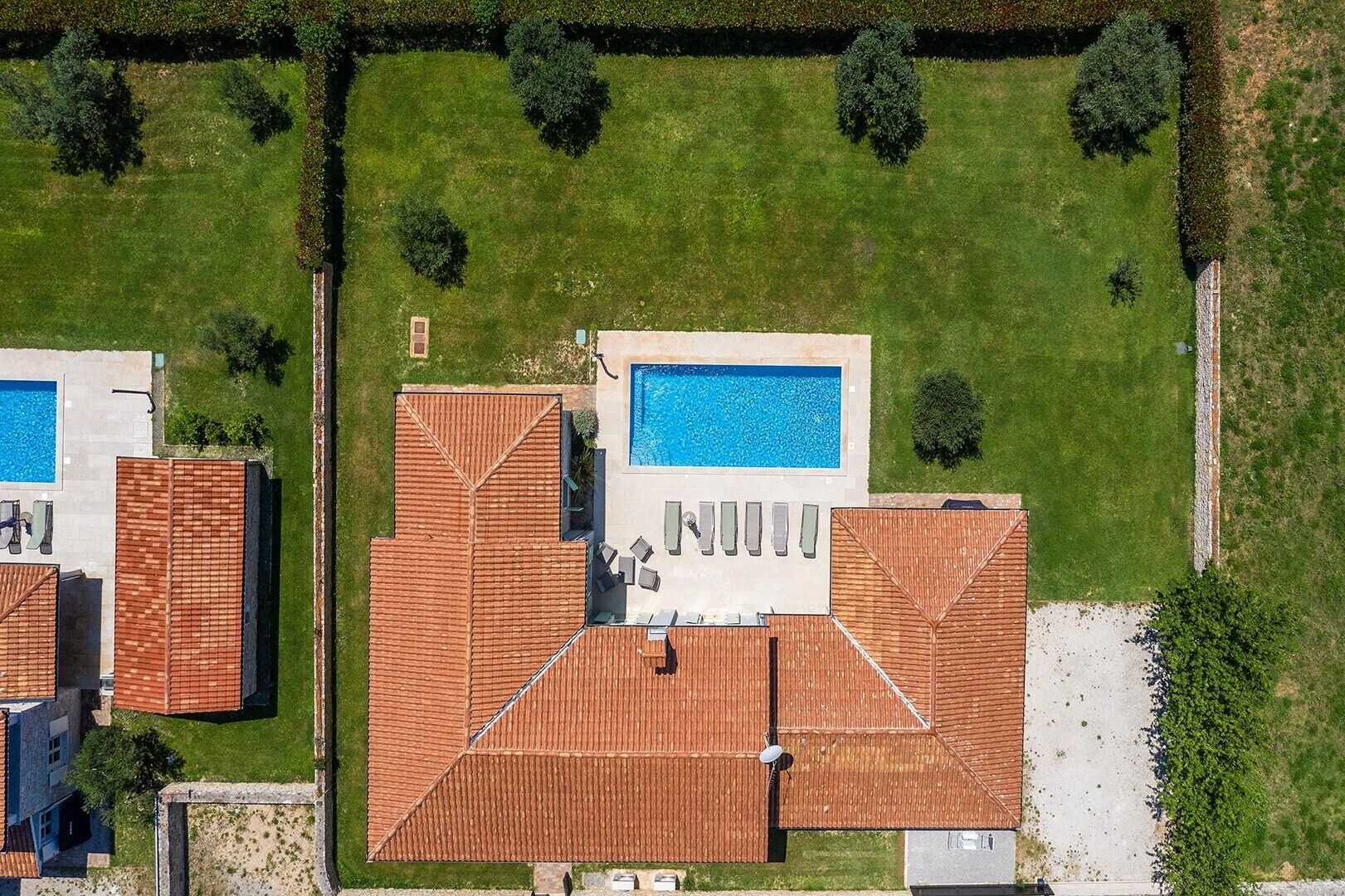 A residential property with a swimming pool, a covered patio, and a well-maintained lawn.
