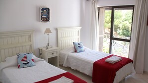 A hotel room with two beds, each with a red and white bedspread, a white headboard, and a small bedside table with a lamp. - Lovely Spacious Apartment Facing South With Sea Views with use of  communal pool (Sesmarias)