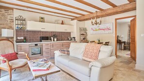 A cozy living room with a sofa, a coffee table with books, and a kitchen in the background.