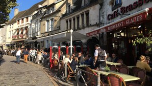 A bustling outdoor café with outdoor seating and a variety of patrons.
